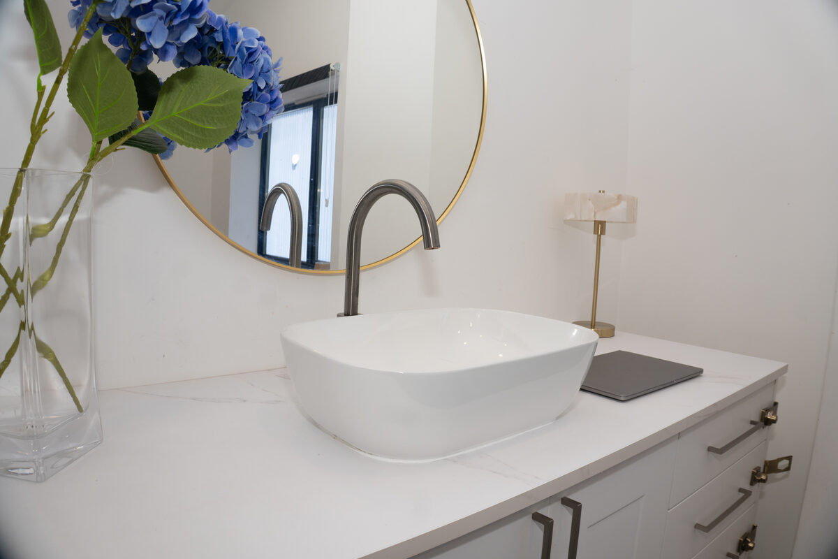 Vanity area with a round gold-framed mirror, vessel basin, and fresh hydrangeas